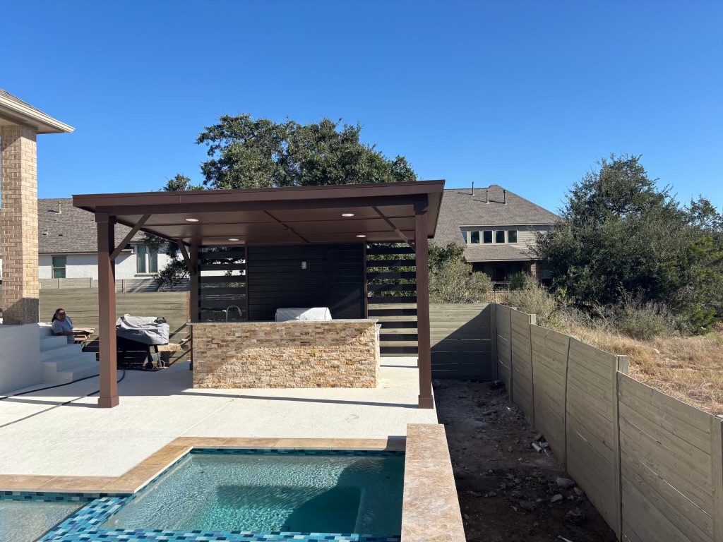 Modern backyard with pool, covered outdoor kitchen, and stone walls
