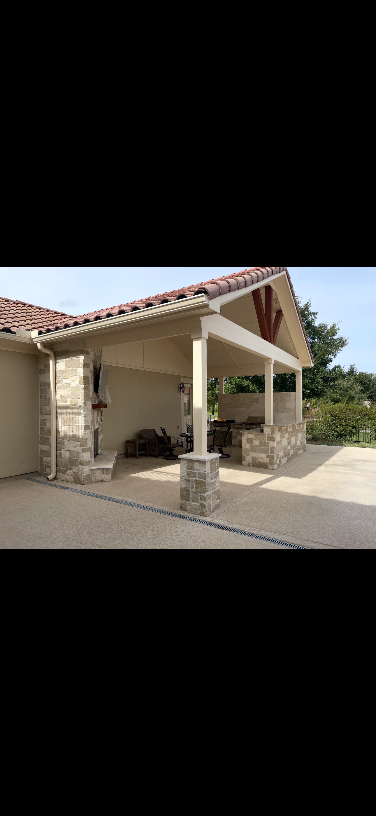 Stone-clad outdoor patio with covered seating area and tile roof